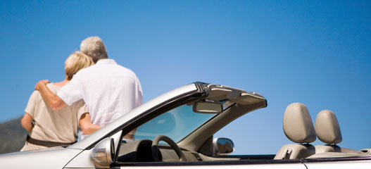 pareja mayor apoyada en el capó del coche