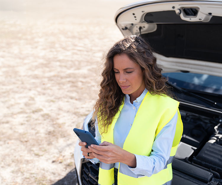 chica haciendo gestiones con el móvil al lado de un coche