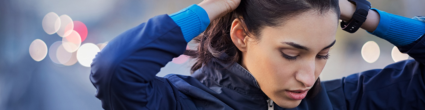 Mujer pensativa mirando hacia abajo mientras se toca la cabeza con la dos manos