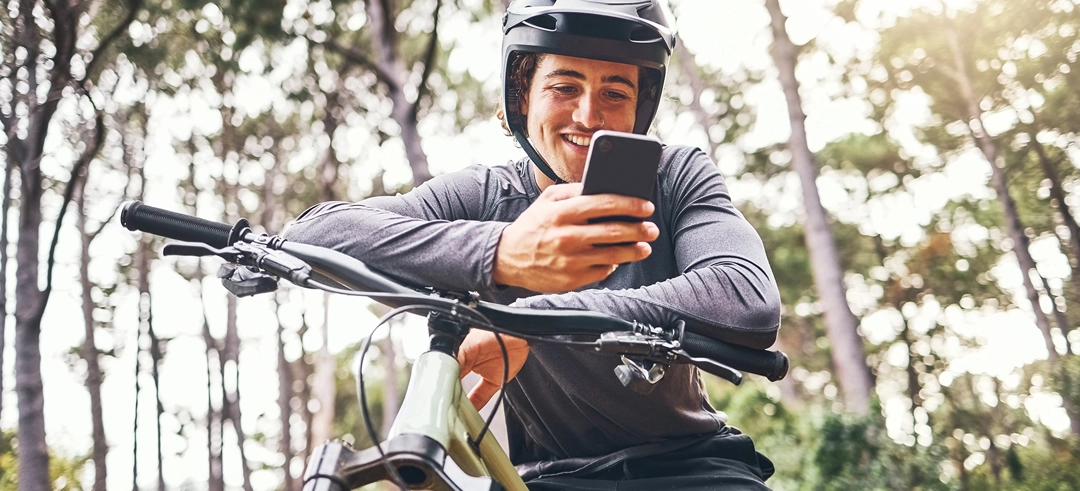 Hombre estacionado con la bicicleta y mirando su smartphone
