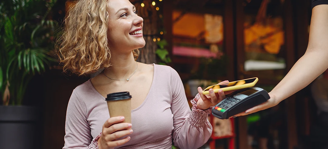 Mujer joven pagando un café con el móvil en un datafono 