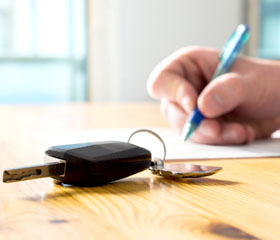 Firma de documentos para una compraventa de un coche con la llaves encima de la mesa