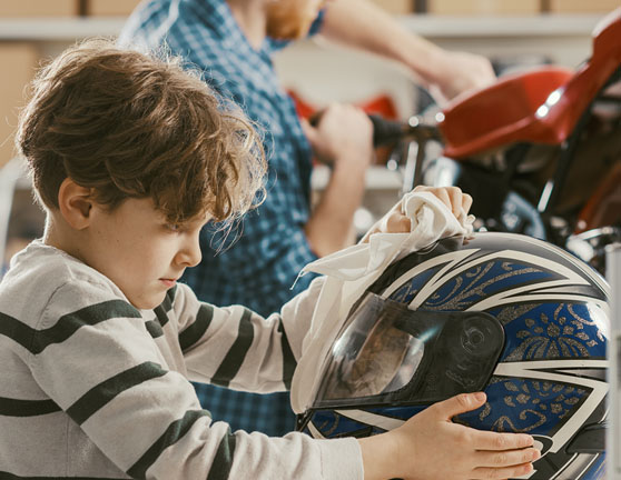 Niño limpiando el casco de una moto